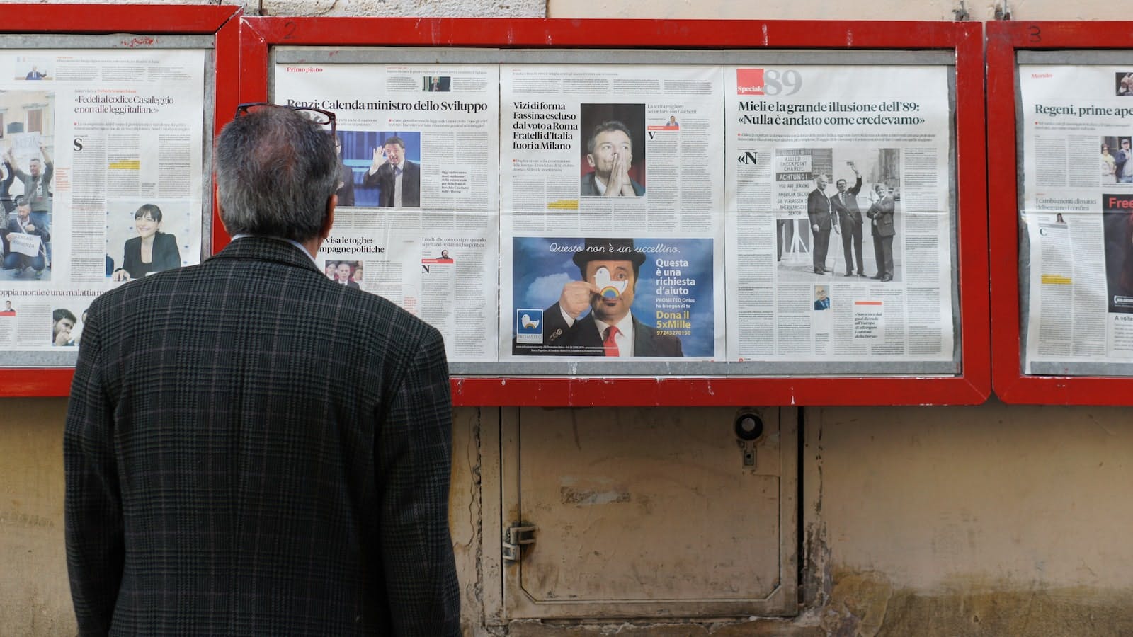 Person looking at a wall of newspapers